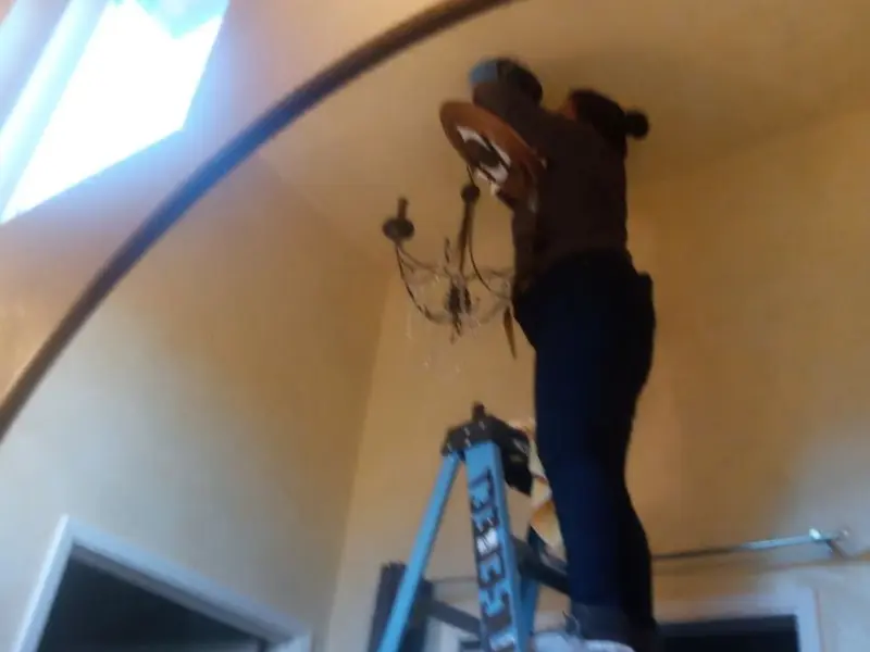Electrician installing a chandelier in a Oxnard residence